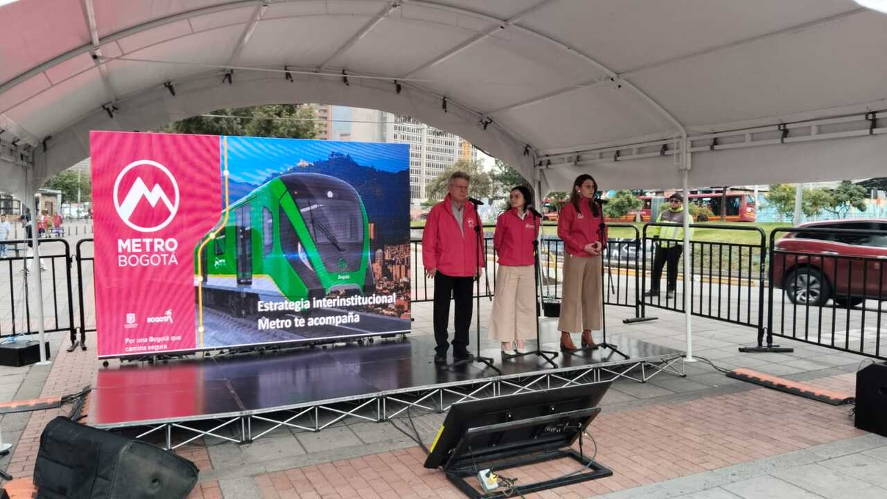 Foto de la tarima con la presentación del evento y el gerente del Metro, la secretaria de Movilidad, y gerente de TransMilenio con micrófonos para hablar al público