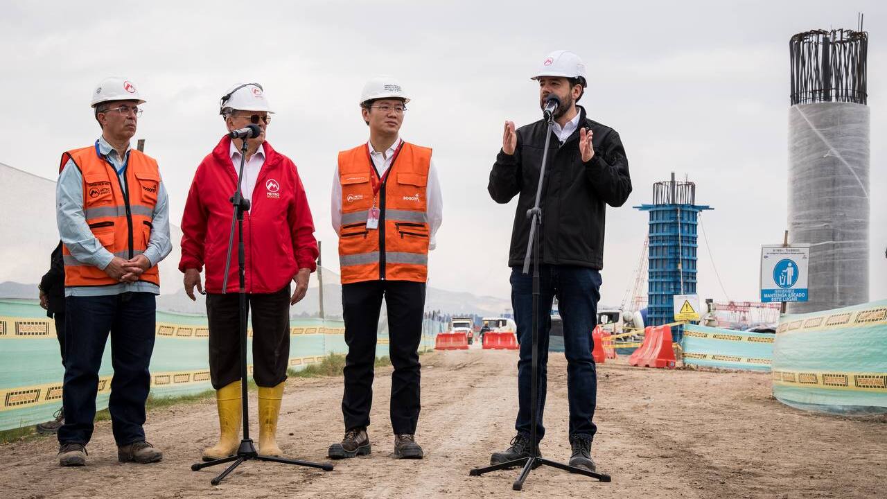 Alcalde Carlos Galán en el micrófono hablando desde el patio taller, junto al gerente del Metro, Wu Yu del concesionario Metro Línea 1 y Javier Descarga de la interventoría